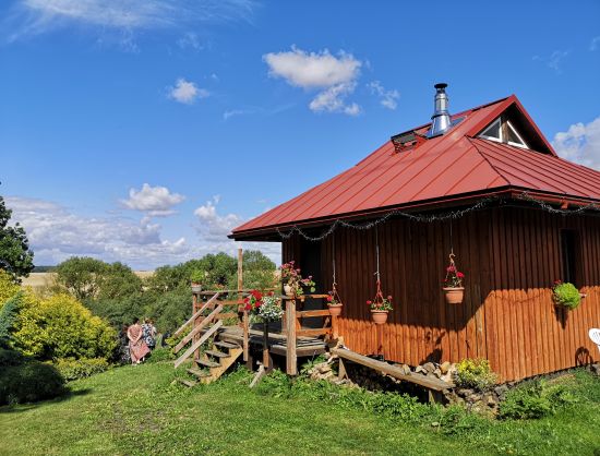 Saimniecības Padegas apskate, ekskursija. Saimniecības ēkas un dārzs vasaras plaukumā, parādot tipisku Latvijas lauku vidi.