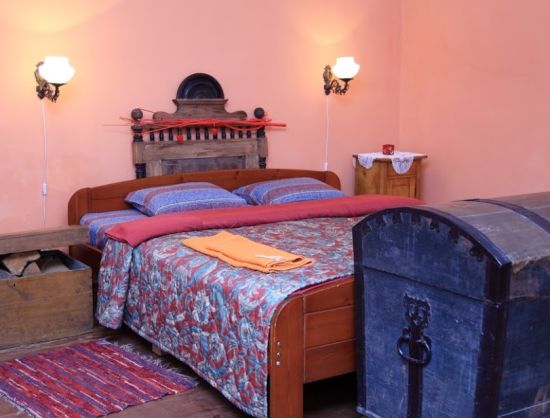 Viesu nama Baltā māja istabas iekārtojums un interjers - Numuri iekārtoti atbilsto&scaron;i 18.gs. kalpu mājas interjeram ar koka gultām un citām koka mēbelēm, austām segām un citiem vēsturiskiem priek&scaron;metiem.